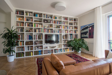 Esempio di un grande soggiorno minimal aperto con libreria, pareti bianche, parquet chiaro, nessun camino, parete attrezzata e pavimento marrone
