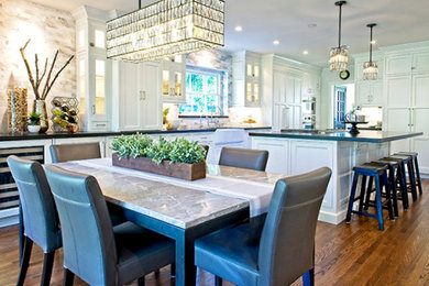 Eat-in kitchen - large craftsman galley medium tone wood floor and brown floor eat-in kitchen idea in Orange County with a farmhouse sink, shaker cabinets, white cabinets, quartz countertops, gray backsplash, marble backsplash, stainless steel appliances, an island and black countertops