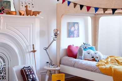 Photo of a modern gender-neutral kids' bedroom for kids 4-10 years old in New York with white walls and medium hardwood floors.
