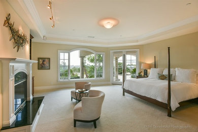 Inspiration for a huge transitional master medium tone wood floor bedroom remodel in Austin with beige walls, a standard fireplace and a wood fireplace surround