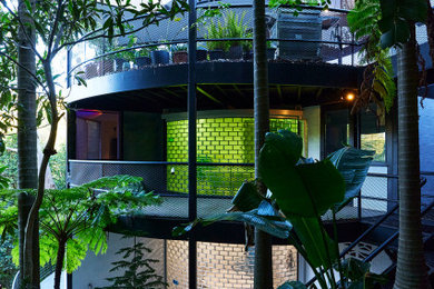 Photo of a large midcentury concrete white house exterior in Sydney with four or more storeys, a flat roof, a metal roof and a grey roof.