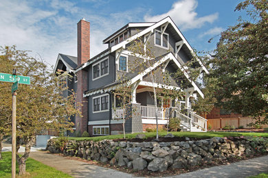 Photo of a mid-sized arts and crafts three-storey grey house exterior in Seattle with wood siding, a gable roof and a shingle roof.
