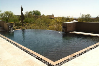 Mid-sized backyard custom-shaped infinity pool in Phoenix with a water feature and tile.