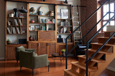 Ejemplo de biblioteca en casa tipo loft moderna con suelo de madera en tonos medios
