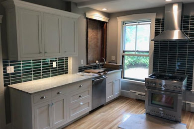 Inspiration for a small modern single-wall light wood floor and brown floor eat-in kitchen remodel in Boston with an undermount sink, shaker cabinets, white cabinets, granite countertops, black backsplash, subway tile backsplash, stainless steel appliances, no island and multicolored countertops
