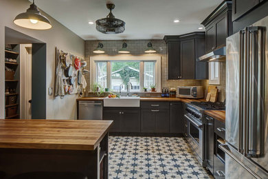 Large farmhouse porcelain tile and blue floor kitchen photo in New York with a farmhouse sink, shaker cabinets, gray cabinets, wood countertops, white backsplash, ceramic backsplash, stainless steel appliances, a peninsula and brown countertops