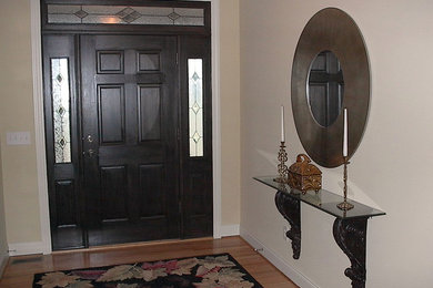 Example of a mid-sized trendy medium tone wood floor entryway design in Other with beige walls and a black front door