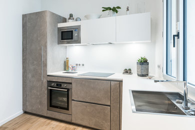 Idée de décoration pour une cuisine ouverte design en L de taille moyenne avec des portes de placard grises, un plan de travail en stratifié, une crédence blanche, sol en stratifié et aucun îlot.