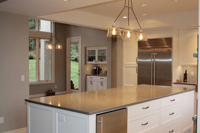 Kitchen - contemporary dark wood floor and brown floor kitchen idea in Seattle with white cabinets, gray backsplash, subway tile backsplash, stainless steel appliances, an island and gray countertops