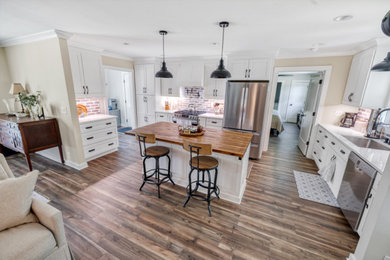 Mid-sized cottage vinyl floor and brown floor kitchen photo in Atlanta with an undermount sink, shaker cabinets, white cabinets, quartz countertops, brown backsplash, brick backsplash, stainless steel appliances, an island and white countertops