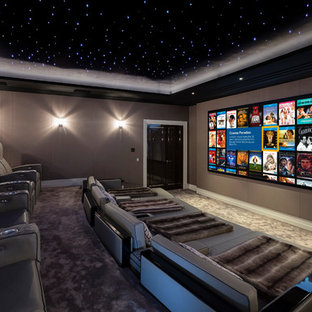 Large contemporary enclosed home cinema in Berkshire with brown walls, carpet and a projector screen.