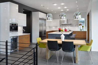 Inspiration for a large l-shaped eat-in kitchen in Edmonton with a double-bowl sink, flat-panel cabinets, white cabinets, quartz benchtops, white splashback, subway tile splashback, stainless steel appliances, slate floors, with island, grey floor and white benchtop.