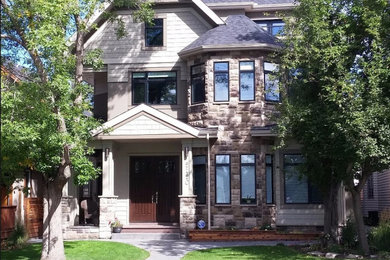 Large arts and crafts three-story mixed siding house exterior photo in Calgary with a shingle roof