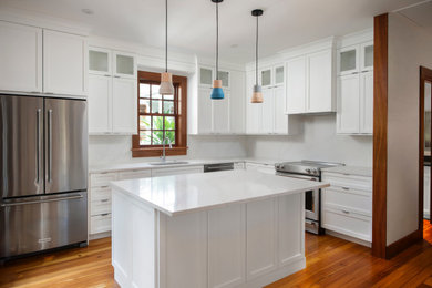 Mid-sized beach style dark wood floor and red floor kitchen photo in Miami with white cabinets, yellow backsplash, stone slab backsplash, stainless steel appliances, an island and white countertops
