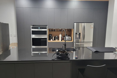 Diseño de cocina comedor moderna con fregadero de un seno, armarios con paneles lisos, encimera de granito, una isla, puertas de armario negras y encimeras negras