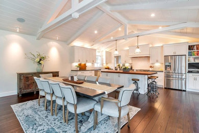 Example of a large farmhouse l-shaped dark wood floor and brown floor eat-in kitchen design in San Francisco with a farmhouse sink, beaded inset cabinets, white cabinets, soapstone countertops, white backsplash, subway tile backsplash, stainless steel appliances, an island and black countertops