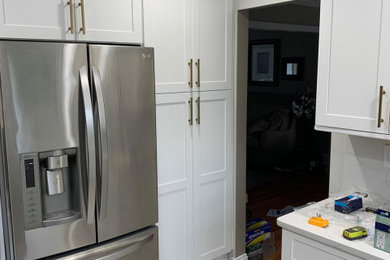 Example of a transitional kitchen pantry design in New York with shaker cabinets, white cabinets, quartz countertops, white backsplash, quartz backsplash, stainless steel appliances and white countertops
