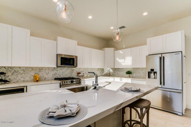 Large transitional l-shaped laminate floor and beige floor eat-in kitchen photo in Denver with an undermount sink, shaker cabinets, white cabinets, marble countertops, multicolored backsplash, mosaic tile backsplash, stainless steel appliances, an island and white countertops