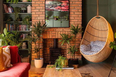 Photo of an eclectic living room in London with green walls, a wood burning stove, a brick fireplace surround and a wallpapered ceiling.