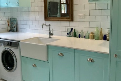Large transitional laundry room in Sydney with a drop-in sink and blue cabinets.