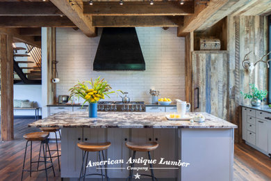 Aménagement d'une cuisine américaine campagne en L avec une crédence blanche, une crédence en brique, un sol en bois brun, îlot, un sol marron et poutres apparentes.
