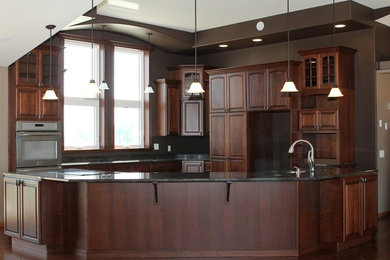 Inspiration for a mid-sized timeless l-shaped dark wood floor eat-in kitchen remodel in Other with an undermount sink, raised-panel cabinets, dark wood cabinets, granite countertops, stainless steel appliances and an island