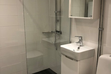 Photo of a mid-sized 3/4 bathroom in Other with flat-panel cabinets, white cabinets, a corner shower, a one-piece toilet, white tile, ceramic tile, ceramic floors, black floor and a shower curtain.