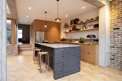 Example of a large l-shaped plywood floor, beige floor and exposed beam eat-in kitchen design in London with a double-bowl sink, flat-panel cabinets, black cabinets, wood countertops, gray backsplash, marble backsplash, paneled appliances, an island and white countertops