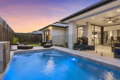 Photo of a mid-sized contemporary backyard custom-shaped pool in Gold Coast - Tweed with tile.
