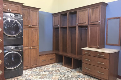 Large elegant l-shaped ceramic tile and multicolored floor laundry room photo in Other with raised-panel cabinets, brown cabinets, laminate countertops, blue walls and a stacked washer/dryer
