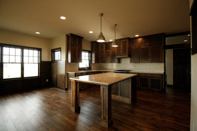 Example of a mid-sized classic u-shaped medium tone wood floor and brown floor eat-in kitchen design in Other with an undermount sink, raised-panel cabinets, medium tone wood cabinets, quartzite countertops, white backsplash, ceramic backsplash, stainless steel appliances and an island