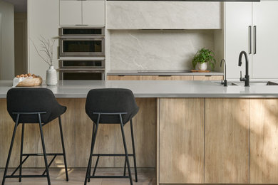 Eat-in kitchen - large contemporary galley light wood floor eat-in kitchen idea in Toronto with a double-bowl sink, flat-panel cabinets, quartz countertops, porcelain backsplash and gray countertops