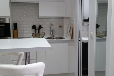 Design ideas for a small contemporary single-wall open plan kitchen in Paris with an undermount sink, white cabinets, white splashback, subway tile splashback, stainless steel appliances, dark hardwood floors, with island and brown floor.