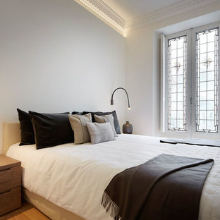 Imagen de dormitorio principal, contemporáneo, de tamaño medio, con paredes blancas, suelo de madera en tonos medios y suelo beige