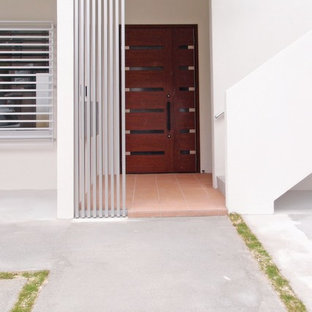Modelo de puerta principal bohemia con paredes blancas, suelo de baldosas de cerámica, puerta de madera oscura y suelo naranja