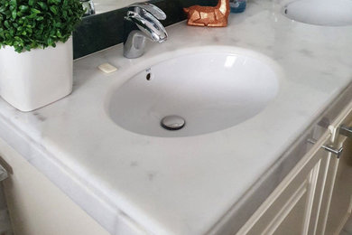 Photo of a medium sized classic grey and white family bathroom in London with shaker cabinets, beige cabinets, a built-in bath, a built-in shower, a two-piece toilet, white tiles, marble tiles, white walls, marble flooring, a submerged sink, marble worktops, white floors, a sliding door, white worktops, double sinks and a built in vanity unit.