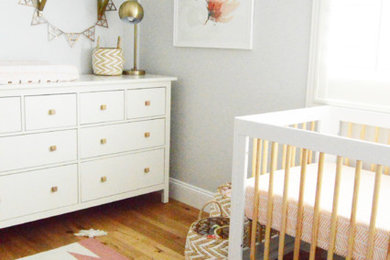 This is an example of a mid-sized transitional nursery for girls in Orange County with grey walls and medium hardwood floors.