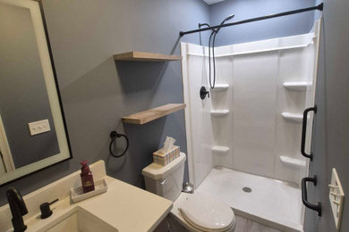 Example of a mountain style 3/4 laminate floor, gray floor and single-sink bathroom design in Other with dark wood cabinets, blue walls, an undermount sink, quartz countertops, white countertops and a built-in vanity