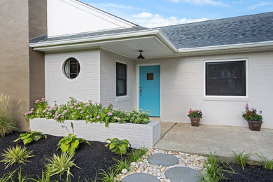 Inspiration for a mid-sized 1950s beige one-story brick exterior home remodel in Wilmington with a shingle roof