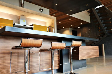 Large trendy l-shaped concrete floor and brown floor eat-in kitchen photo in Vancouver with a drop-in sink, flat-panel cabinets, medium tone wood cabinets, solid surface countertops, stainless steel appliances and an island