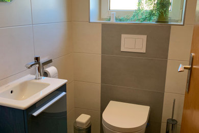 Kleines Modernes Badezimmer mit grauen Schränken, Wandtoilette, braunen Fliesen, brauner Wandfarbe, integriertem Waschbecken, Mineralwerkstoff-Waschtisch, braunem Boden und Einzelwaschbecken in Sonstige
