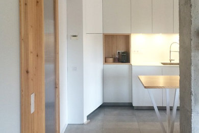 Inspiration for a small modern galley open plan kitchen in Barcelona with a single-bowl sink, flat-panel cabinets, white cabinets, white splashback, panelled appliances, porcelain floors and with island.