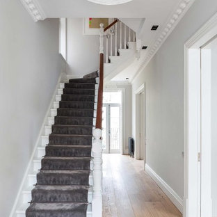 This is an example of a large modern carpeted curved staircase in London with carpeted risers.