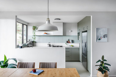 Photo of a mid-sized midcentury u-shaped eat-in kitchen in Brisbane with flat-panel cabinets, green cabinets, stainless steel appliances, a peninsula, grey floor, white benchtop and an undermount sink.