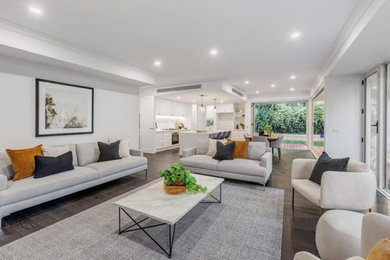 This is an example of a large modern open concept living room in Melbourne with dark hardwood floors, a standard fireplace, a plaster fireplace surround and recessed.