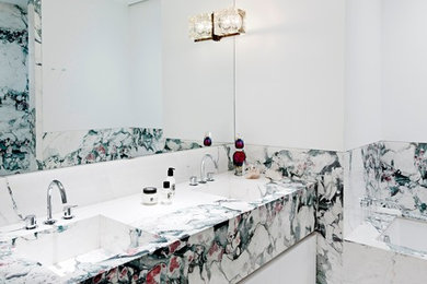 Inspiration for a contemporary bathroom in New York with an integrated sink, flat-panel cabinets, white cabinets, an undermount tub, multi-coloured tile, white walls and marble.