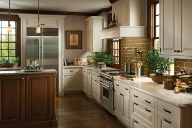 Example of a large classic l-shaped dark wood floor and brown floor eat-in kitchen design in Philadelphia with raised-panel cabinets, beige cabinets, granite countertops, green backsplash, subway tile backsplash, stainless steel appliances and an island
