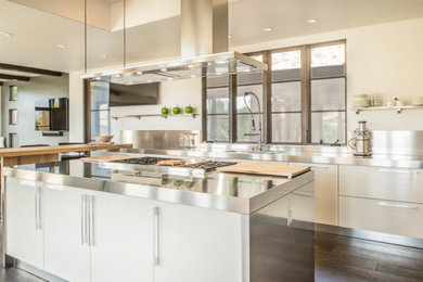Eat-in kitchen - large modern single-wall dark wood floor eat-in kitchen idea in Santa Barbara with an integrated sink, white cabinets, stainless steel appliances, an island, stainless steel countertops, metallic backsplash, metal backsplash and flat-panel cabinets