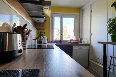 Cette image montre une cuisine minimaliste en L fermée et de taille moyenne avec un évier 1 bac, des portes de placard grises, une crédence blanche, une crédence en bois, un électroménager en acier inoxydable, un sol en carrelage de céramique, un sol gris et un plan de travail beige.