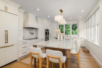 Example of a transitional l-shaped medium tone wood floor and brown floor kitchen design in DC Metro with shaker cabinets, white cabinets, stainless steel appliances, an island and gray countertops